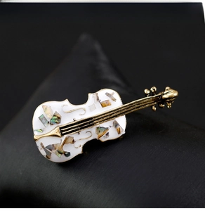 Macro shot of retro cello brooch with golden frame and iridescent shell inlay details