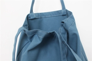 Detail of blue canvas tote bag showing thick fabric texture and white contrast stitching