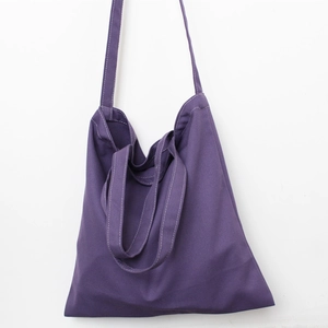 Detailed view of purple canvas tote bag featuring double handles and long shoulder strap