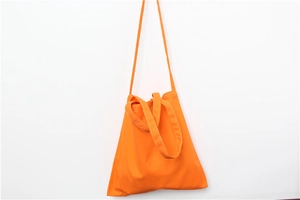 Detail of bright orange canvas tote bag showing high-density texture and dual strap design