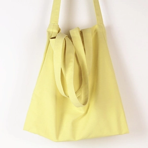 Detail of light yellow canvas tote bag fabric texture with long shoulder straps