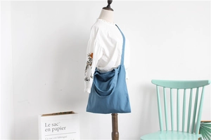 Blue canvas crossbody bag detail showing capacity and drape on model in casual style