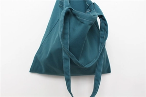 Detail view of dark teal canvas tote showing white contrast stitching and durable texture
