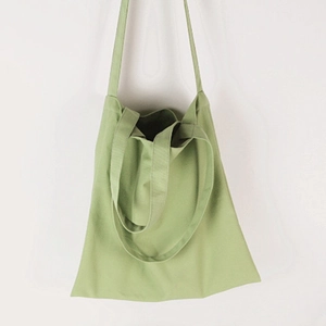 Detail of light green canvas tote bag with dual shoulder straps and hand carry handles