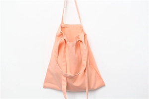 Detail of light orange canvas tote bag showing soft cotton texture and dual handles