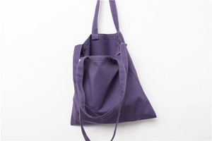 Detail of purple canvas tote bag featuring white contrast stitching and durable shoulder strap