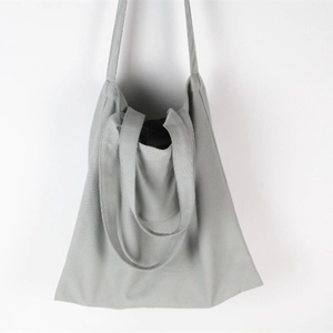 Detail of grey canvas tote bag featuring dual long straps and short hand-carry handle
