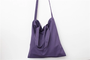 Detailed view of purple canvas tote bag with white contrast stitching and shoulder strap