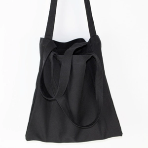 Detail view of simple black canvas tote bag with dual handles on white background