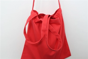 Close-up of red canvas tote bag showing white contrast stitching and durable handles