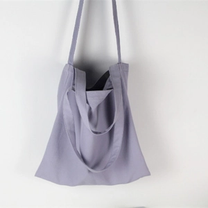Detailed view of light purple canvas tote bag hanging against a white wall for daily use