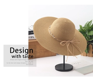 Detail of khaki wide brim straw hat with beaded bow tie on elegant wooden display