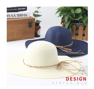 Detail of wide brim straw hats with woven bead rope and tassel bow for summer beach
