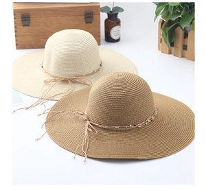 Detailed macro view of woven straw hats featuring navy beads and rustic rope accents
