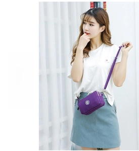Paarse nylon crossbody tas met meerdere ritsen getoond door een vrouwelijk model