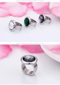Detail of faceted round gemstone rings in green, white, and black with a wide band