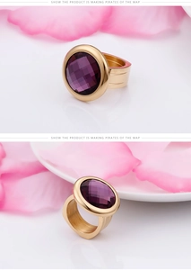 Dettaglio macro di un anello dorato con grande pietra viola sfaccettata e fascia spessa
