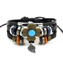 Detail of woven black leather bracelet with bronze flower and silver leaf pendant