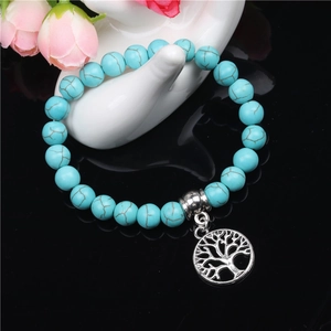 Turquoise 8mm beads bracelet with silver Tree of Life charm on a reflective background