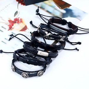 Detailed set of multilayer leather bracelets featuring metal charms and braided cords