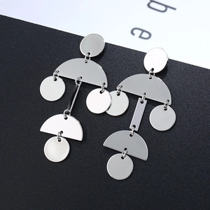 Detailed view of silver geometric dangle earrings with metallic circular pendants