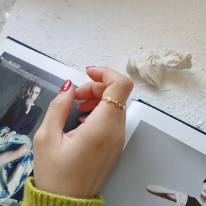 Detailed shot of a thin 18K gold minimalist ring with small disc charms on a model finger