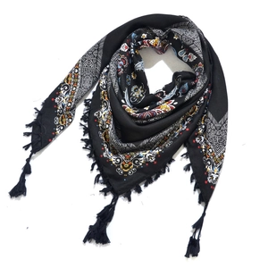 Detailed view of bohemian floral geometric pattern and tassel fringe on black scarf