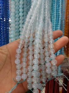 Close-up of 8mm light blue natural stone beads held in hand with assorted crystal strands