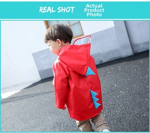 Detail of red dinosaur raincoat featuring blue spine spikes and a clear brim hood