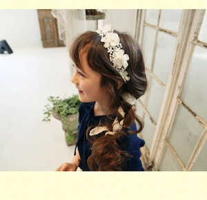 Detalle de una niña con diadema de encaje blanco con flores, perlas y cintas sueltas
