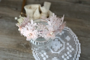 Detalle de diadema de flores de encaje rosa con perlas sobre una superficie de madera