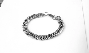 Close-up of polished silver stainless steel Cuban link bracelet with lobster clasp detail