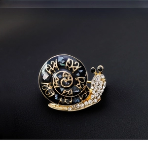 Detailed close-up of a vintage snail brooch featuring deep blue enamel and sparkling crystals