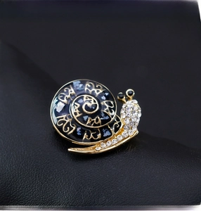 Detailed close-up of a vintage gold snail brooch with blue enamel and sparkling inlay