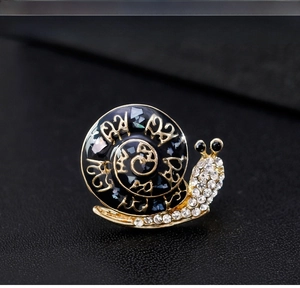 Macro shot of snail brooch with black enamel shell and sparkling white crystals
