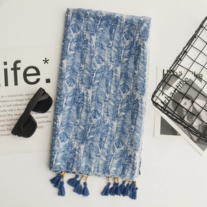 Close-up of blue feather print cotton linen scarf with handmade beaded tassel detail