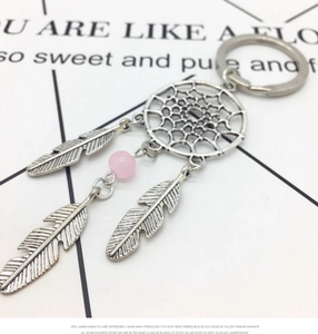Detail of silver dreamcatcher keychain with three metal feathers and a pink bead pendant