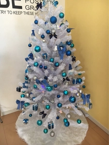 Detail of a white faux fur Christmas tree skirt with festive blue and silver ornaments