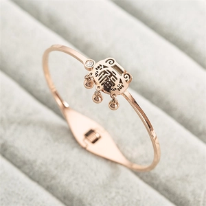 Détail de la gourmette rose dorée avec pendentif cadenas, cloches et cristal