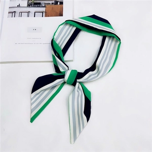 Dettaglio di un foulard in seta a righe annodato a fiocco nei colori verde, bianco e nero