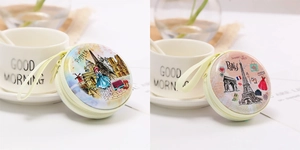 Detail of round tinplate coin purses featuring Parisian landmarks and zipper closure
