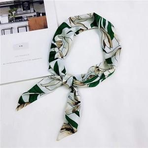 Dettaglio della sciarpa in seta a fiori verdi e bianchi con un nodo decorativo pre-annodato