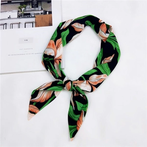 Dettaglio di un foulard in raso con stampa floreale tropicale annodato su sfondo bianco