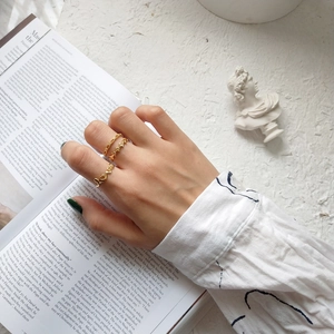 Detailed view of three gold rings featuring heart and olive leaf designs on a magazine