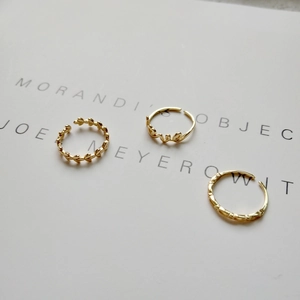Detailed view of three gold 925 silver rings with leaf and LOVE letter designs
