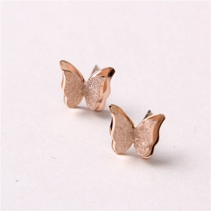 Macro detail of rose gold butterfly earrings with matte and polished textures