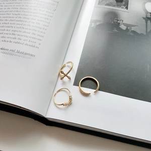Detailed view of three gold-plated 925 silver rings with cubic zirconia on a book