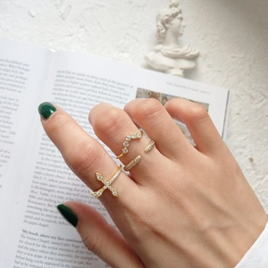 Close-up of elegant 18K gold-plated sterling silver rings with zircon cross and wave detail