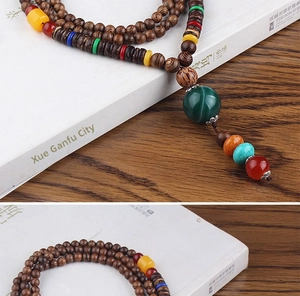 Detailed shot of ethnic wooden prayer beads necklace with colorful spacer beads and green pendant