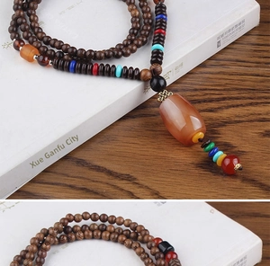 Detailed view of ethnic wood bead necklace featuring a large orange agate stone pendant